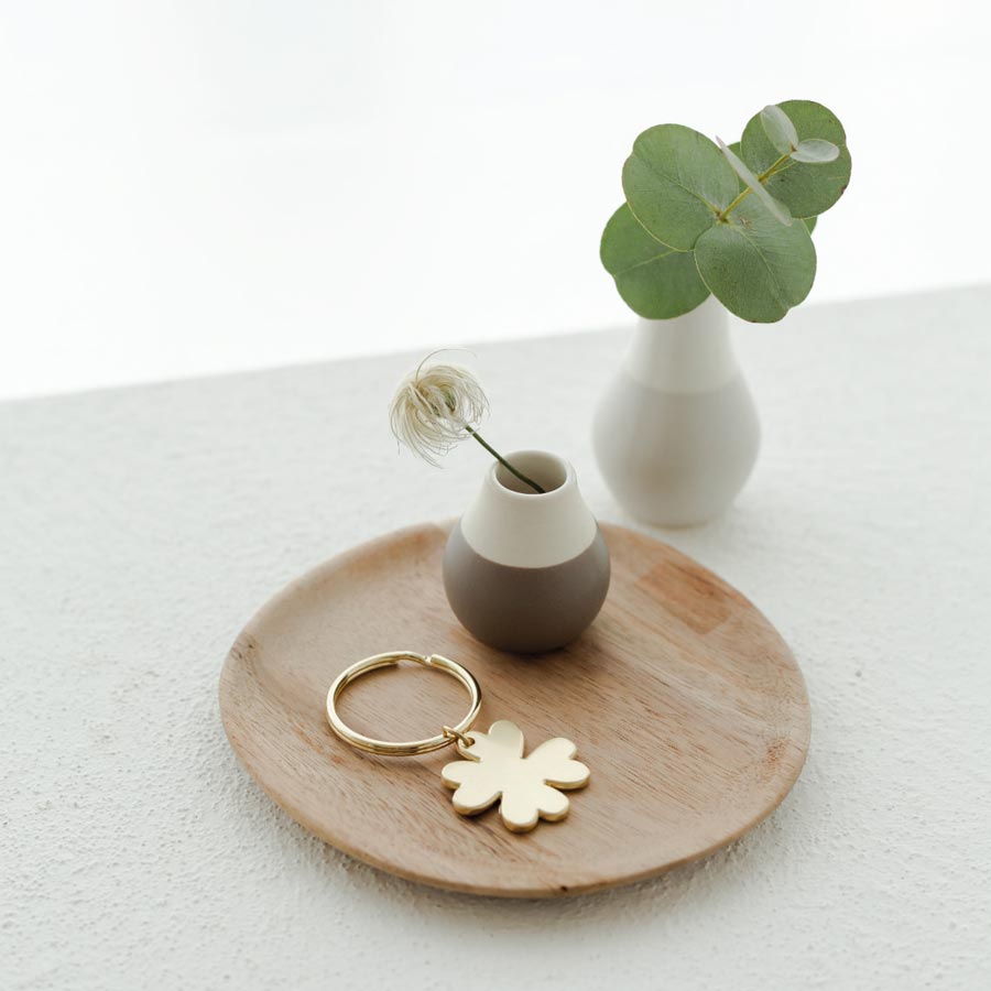 Schlüsselanhänger mit Kleeblatt auf Dekoteller mit Vase dekoriert.